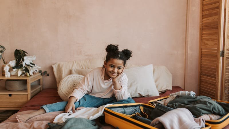 Niña sonriendo mientras prepara su equipaje para el campamento