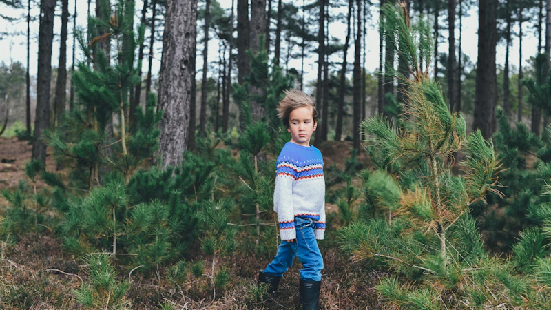 Niño con ropa cómoda jugando entre árboles en el campo