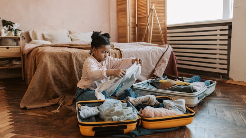 Niña organizando su ropa en la maleta antes de ir al campamento
